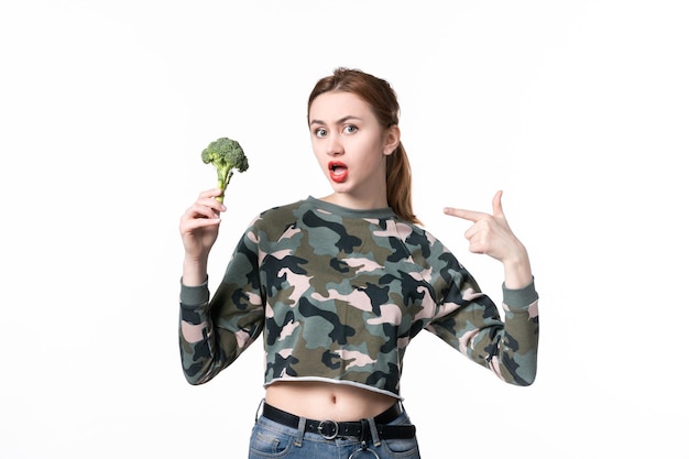 Vista frontal de las hembras jóvenes sosteniendo poco brócoli sobre fondo blanco comida dieta ensalada plato cuerpo almuerzo salud alimentaria