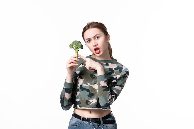 Vista frontal de las hembras jóvenes sosteniendo poco brócoli sobre fondo blanco, comida para ensaladas, dieta, plato de salud, comida para el cuerpo, almuerzo