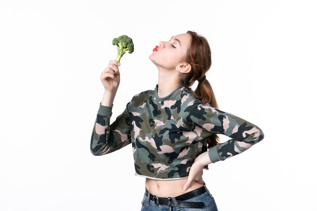 Vista frontal de las hembras jóvenes sosteniendo poco brócoli verde sobre fondo blanco plato almuerzo comida corporal ensalada horizontal dieta comida