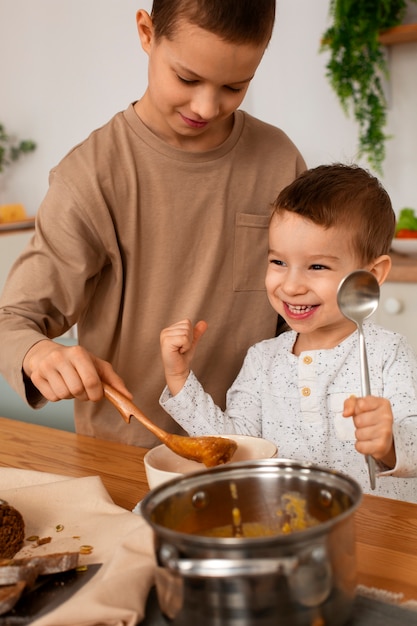 Foto gratuita vista frontal hermanos con comida en casa.