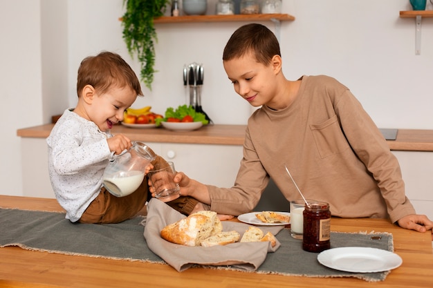 Foto gratuita vista frontal hermanos con comida en casa.