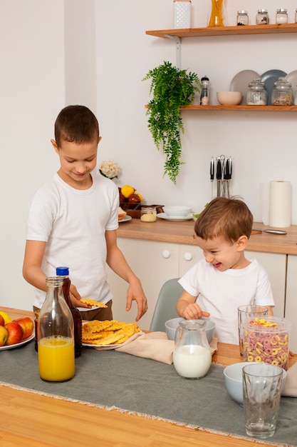 Foto gratuita vista frontal hermanos con comida en casa.