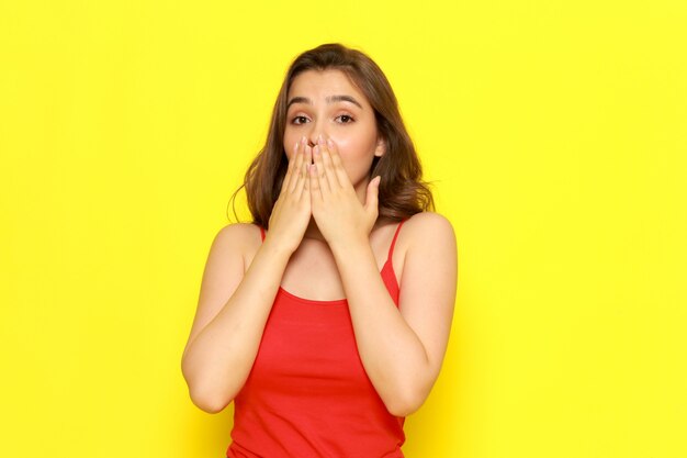 Una vista frontal hermosa joven en camisa roja y jeans azul posando con expresión sorprendida