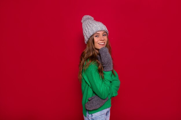 Vista frontal de la hermosa joven con gorro de punto y suéter verde