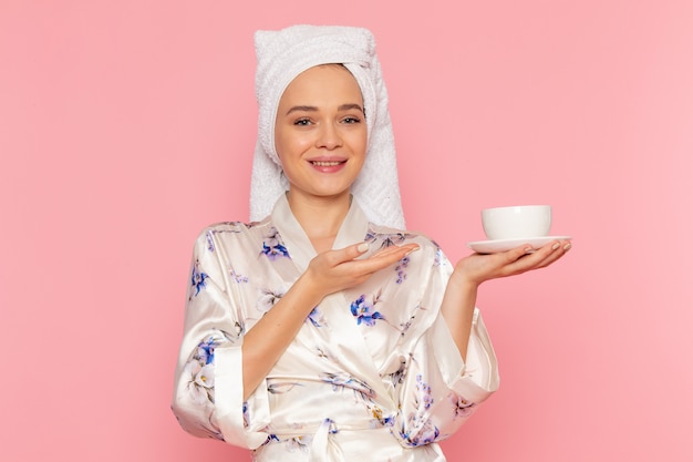 Foto gratuita una vista frontal hermosa jovencita en bata de baño con taza de café