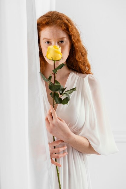 Vista frontal de la hermosa mujer posando con una flor de primavera