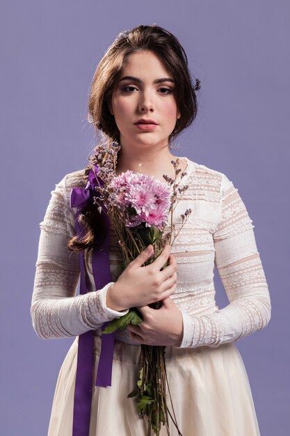 Vista frontal de la hermosa mujer posando con ramo de flores