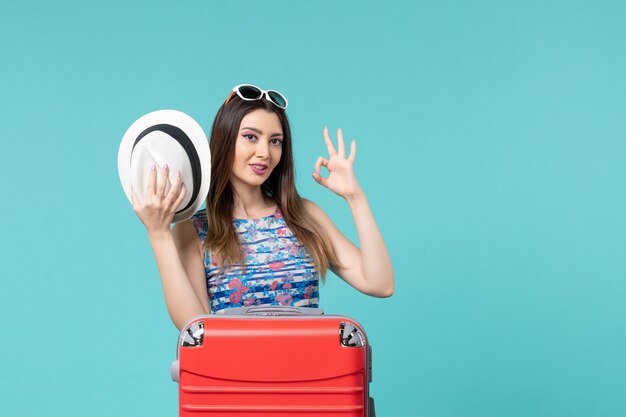 Vista frontal hermosa mujer preparándose para las vacaciones con bolsa roja y sombrero en el espacio azul