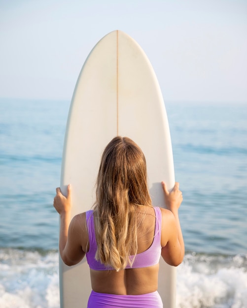 Vista frontal de la hermosa mujer con tabla de surf