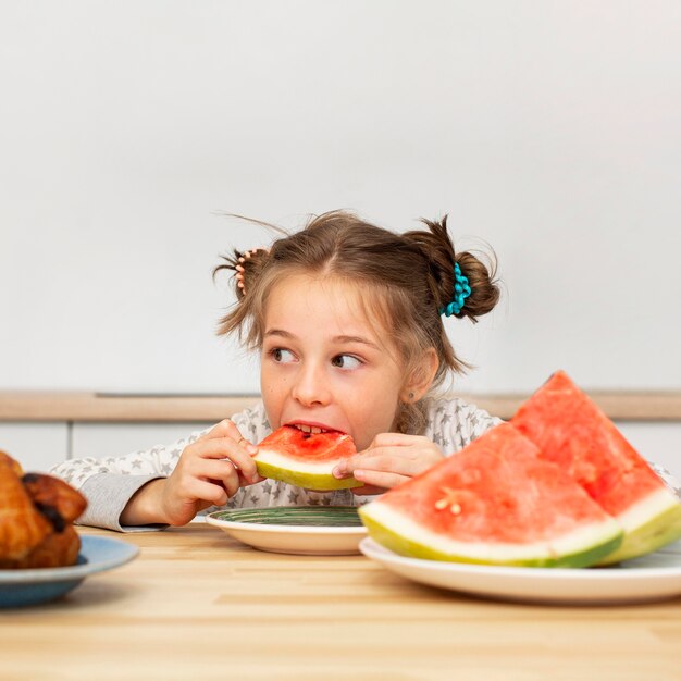 Vista frontal de la hermosa niña comiendo sandía