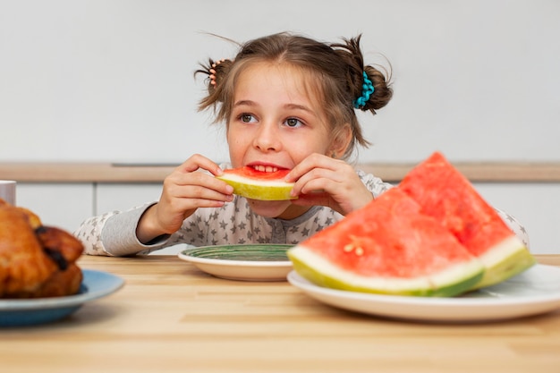 Vista frontal de la hermosa niña comiendo sandía