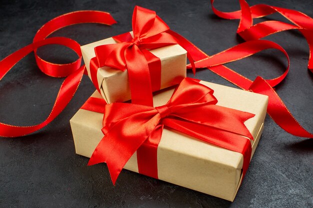 Vista frontal de hermosos regalos con cinta roja sobre fondo oscuro