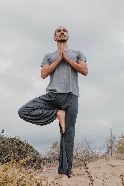 Foto gratuita vista frontal del hombre afuera en posición de yoga