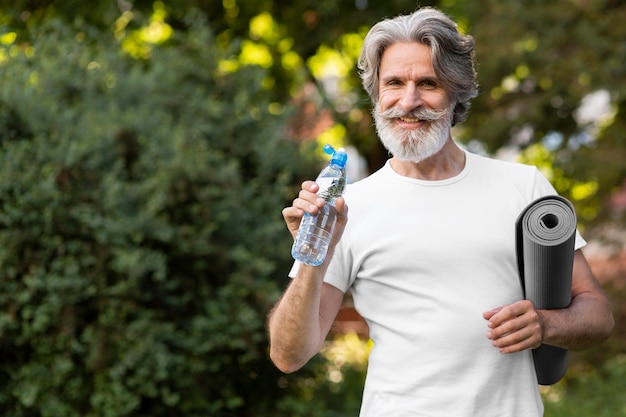 Foto gratuita vista frontal hombre con agua y colchoneta de yoga