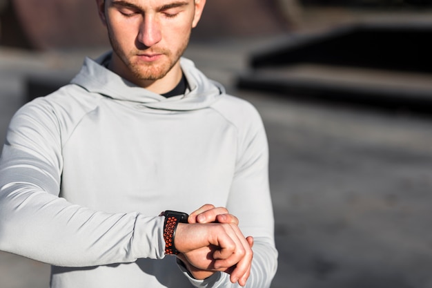 Vista frontal hombre ajustando su reloj deportivo