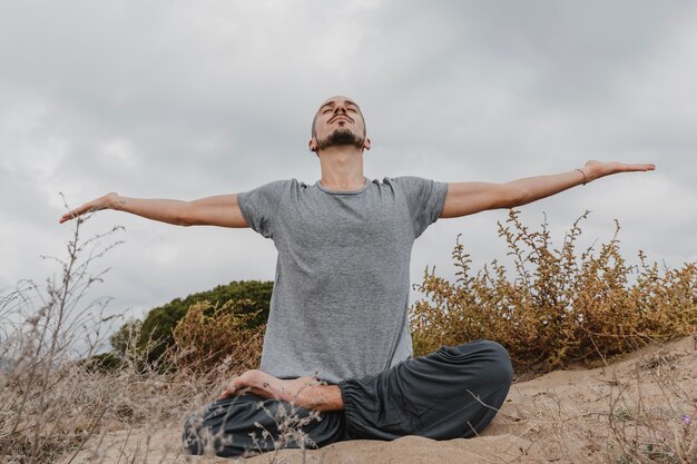 Vista frontal del hombre al aire libre haciendo yoga