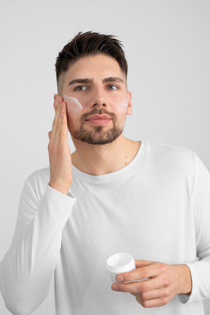 Vista frontal hombre aplicando crema facial