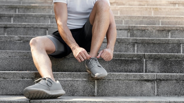 Vista frontal del hombre atando sus cordones antes de hacer ejercicio