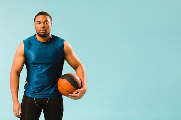 Vista frontal del hombre en athleisure sosteniendo baloncesto