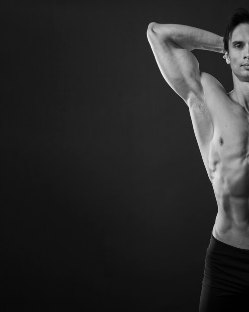 Vista frontal del hombre atlético mostrando bíceps en blanco y negro