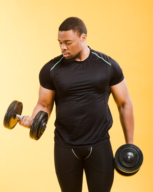 Vista frontal del hombre atlético con pesas en traje de gimnasio