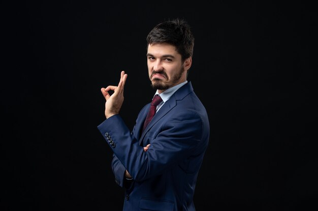 Vista frontal del hombre barbudo emocional haciendo un gesto perfecto en la pared oscura aislada