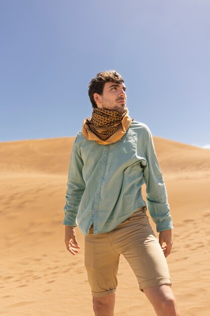 Vista frontal hombre con bufanda en el desierto