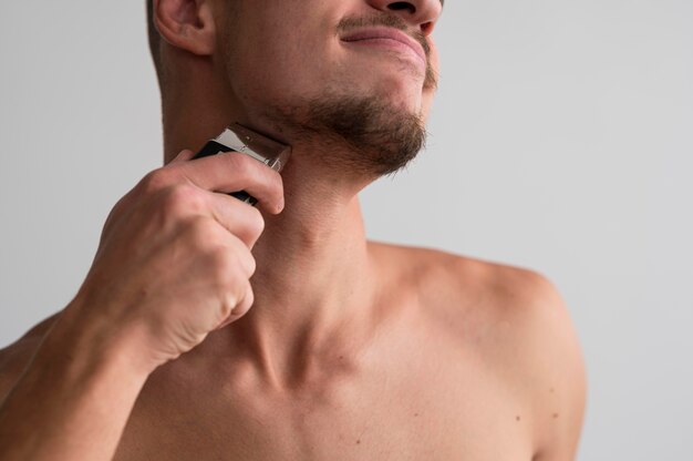 Foto gratuita vista frontal del hombre sin camisa con afeitadora eléctrica