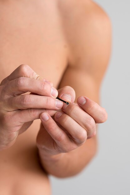 Vista frontal del hombre sin camisa cuidando sus uñas