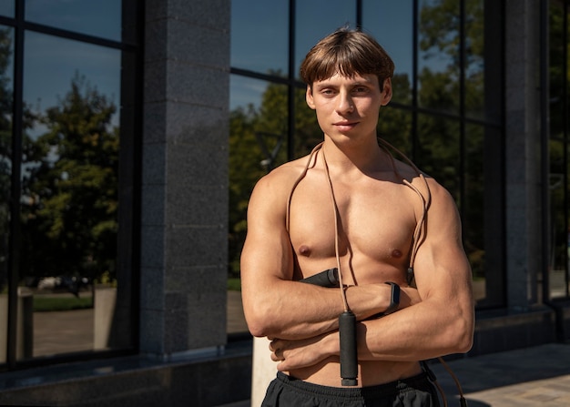 Vista frontal del hombre sin camisa posando con saltar la cuerda