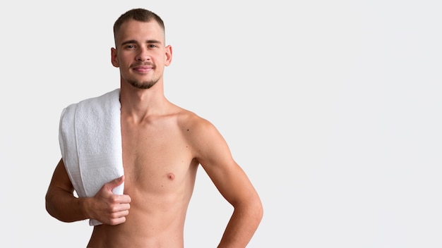 Vista frontal del hombre sin camisa posando con toalla y espacio de copia