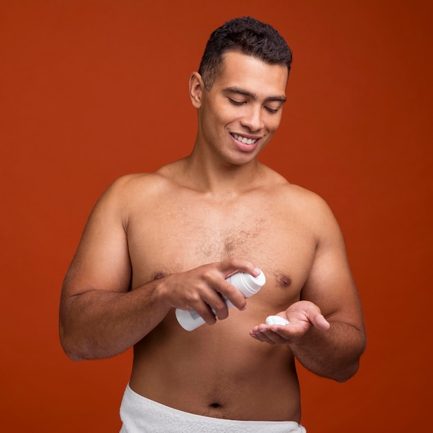 Vista frontal del hombre sin camisa sonriente con espuma de afeitar