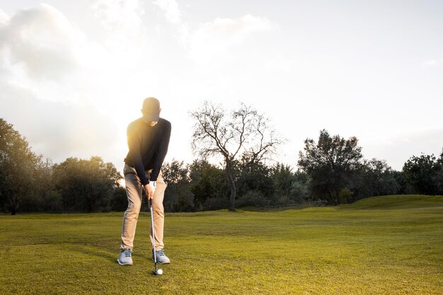 Vista frontal del hombre en el campo de golf cubierto de hierba