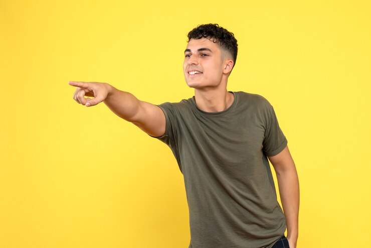 Vista frontal de un hombre el chico sonriente señala con el dedo hacia un lado