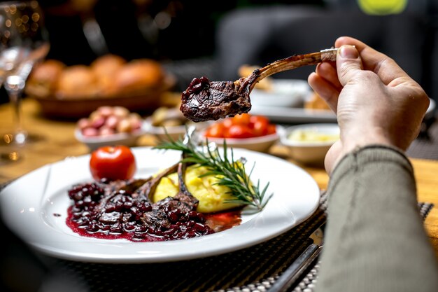 Vista frontal un hombre come costillas de cordero fritas en salsa de granada