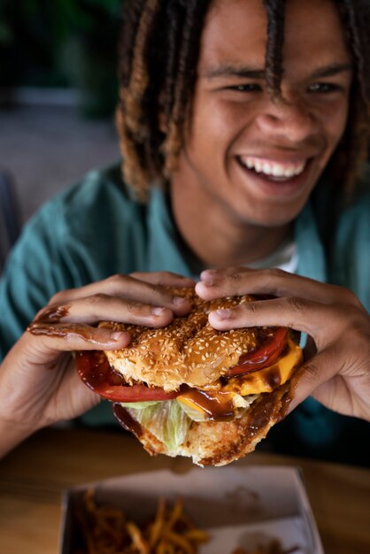 Vista frontal hombre comiendo hamburguesa de una manera divertida