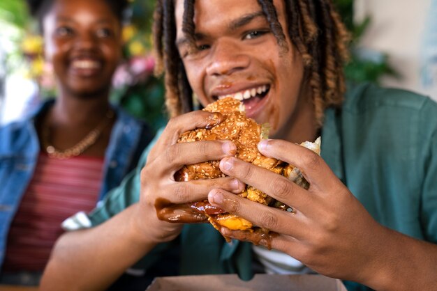 Vista frontal hombre comiendo hamburguesa de una manera divertida