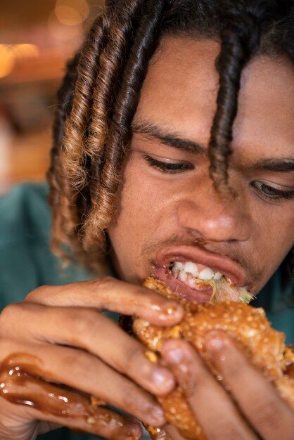 Vista frontal hombre comiendo hamburguesa de una manera divertida