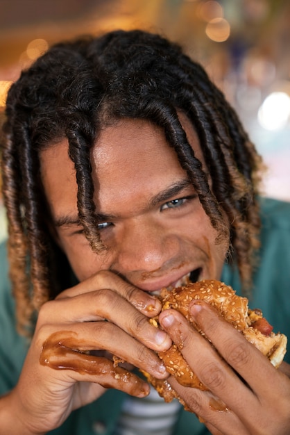 Vista frontal hombre comiendo hamburguesa de una manera divertida