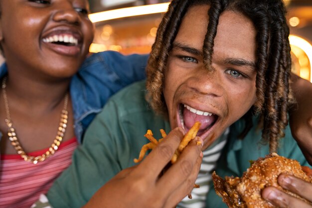 Vista frontal hombre comiendo hamburguesa de una manera divertida