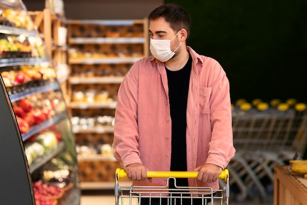 Vista frontal hombre de compras con máscara