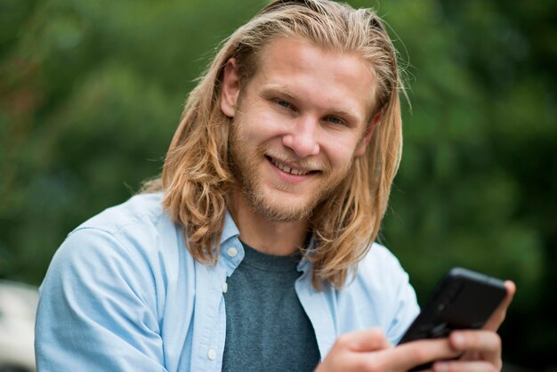 Vista frontal del hombre feliz al aire libre con teléfono