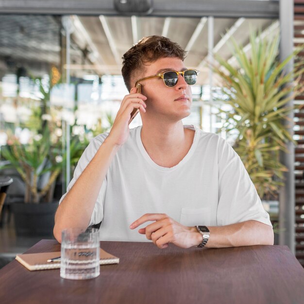 Vista frontal del hombre con gafas de sol hablando por teléfono en el pub