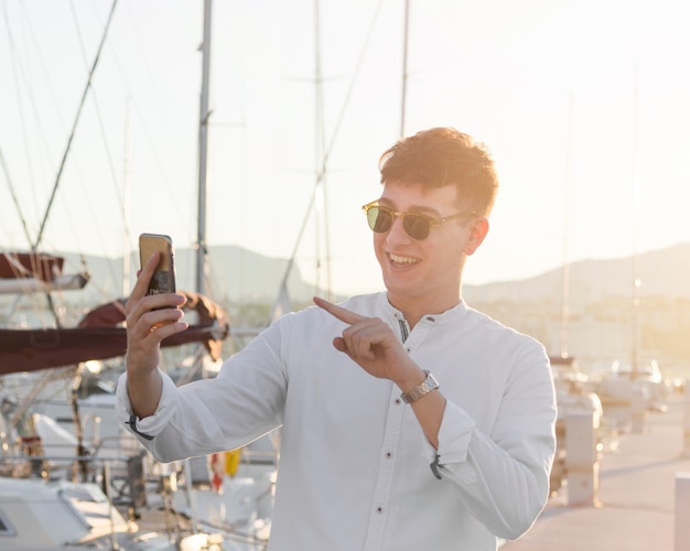 Vista frontal del hombre con gafas de sol con una videollamada en el puerto deportivo