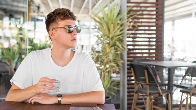 Vista frontal del hombre con gafas con un vaso de agua en el pub