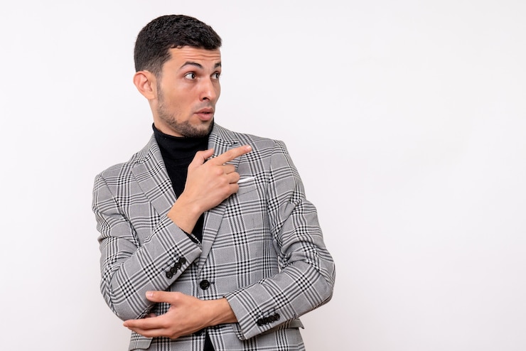 Foto gratuito vista frontal hombre guapo en traje apuntando a la derecha de pie sobre fondo blanco.