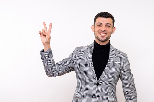 Vista frontal del hombre guapo en traje haciendo el signo de la victoria de pie sobre fondo blanco.