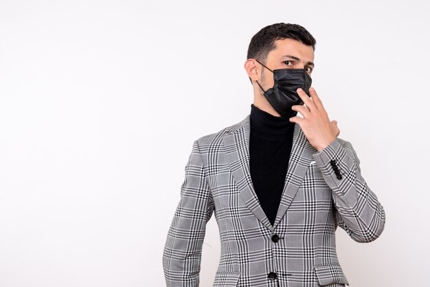 Vista frontal hombre guapo en traje con máscara de pie sobre fondo blanco aislado