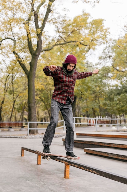 Foto gratuita vista frontal del hombre haciendo trucos con patineta fuera