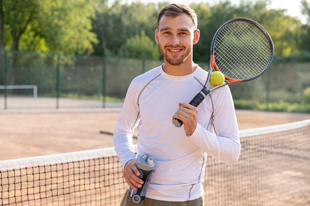 Vista frontal hombre hidratante en cancha de tenis